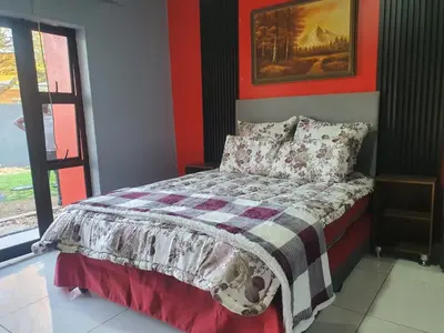 a bedroom with a bed with a red wall at Stofberg Guest House in Brits