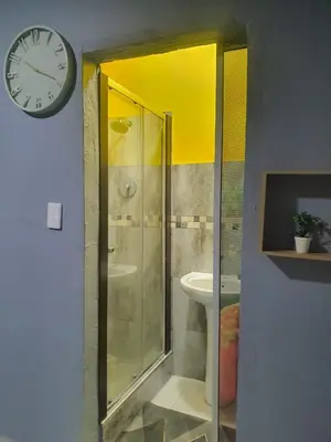 a bathroom with a shower and a clock on the wall at Stofberg Guest House in Brits