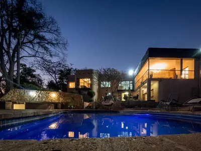 a swimming pool in front of a house at night at 8 On Penny Guesthouse in Nelspruit