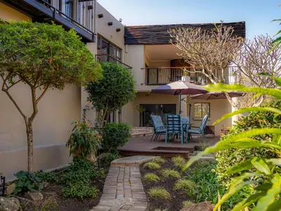 a house with a patio with chairs and an umbrella at 8 On Penny Guesthouse in Nelspruit