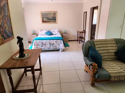 a bedroom with a bed and a table and a chair at La Siesta in Pretoria
