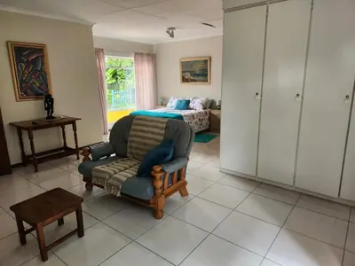 a living room with a chair and a bed at La Siesta in Pretoria