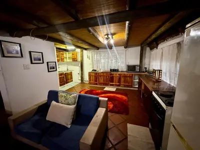 a living room with a couch and a kitchen at The Treehouse in Pretoria