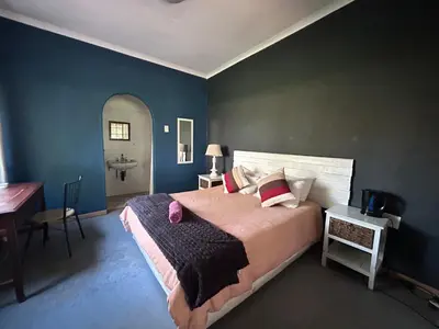 a bedroom with a bed and a desk and a sink at Africa Skye Venue & Events in Pretoria