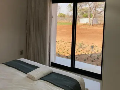 a bed in a room with a large window at Alldays Country Lodge in Alldays