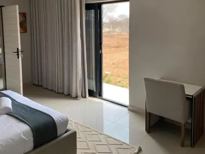 a bedroom with a bed and a desk and a window at Alldays Country Lodge in Alldays