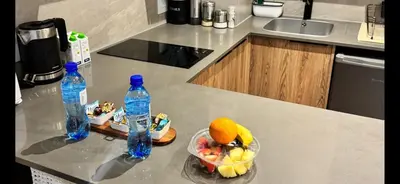 two bottles of water and a bowl of fruit on a kitchen counter at Home at 422Trilogy Menlyn Maine in Pretoria