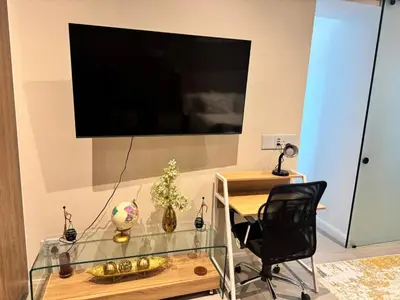 a glass table with a black chair and a television on a wall at Home at 422Trilogy Menlyn Maine in Pretoria