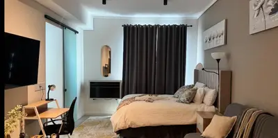 a bedroom with a bed and a desk and a television at Home at 422Trilogy Menlyn Maine in Pretoria