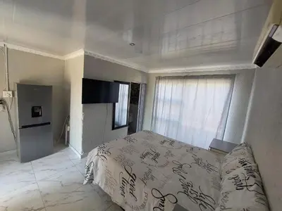 a white bedroom with a bed and a window at Baraba's guest house in Nelspruit