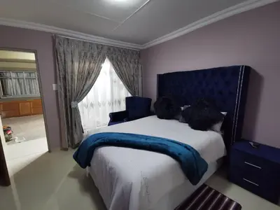 a bedroom with a bed with a blue headboard and a window at Blackpony Guesthouse in Kriel