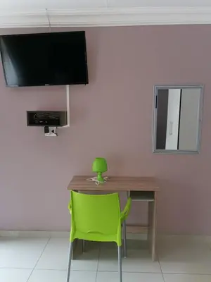 a desk with a green chair and a television on a wall at Blackpony Guesthouse in Kriel
