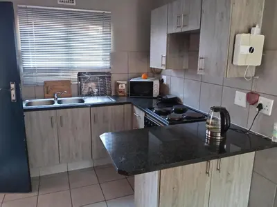 a kitchen with wooden cabinets and a black counter top at Pretoria east N4 rest and drive in Pretoria