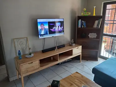a living room with a television on a wooden entertainment center at Pretoria east N4 rest and drive in Pretoria