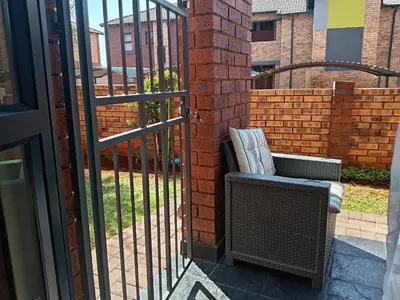 an iron gate with a chair next to a brick fence at Pretoria east N4 rest and drive in Pretoria