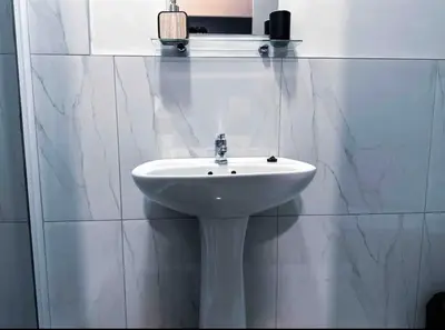 a white sink in a white tiled bathroom at Luxurious 2 bedroom Apartment! in Centurion