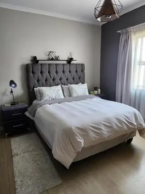 a bedroom with a large bed with a large headboard at Pearl Palace in Polokwane