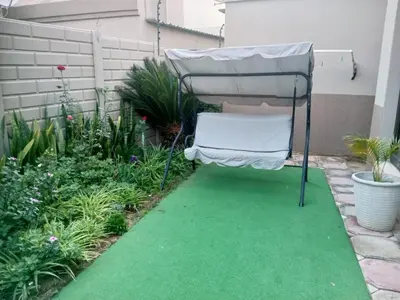 a chair sitting on a green lawn in a garden at Pearl Palace in Polokwane