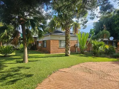 a brick house with palm trees in front of it at The Bushveld Jasmine in Mokopane