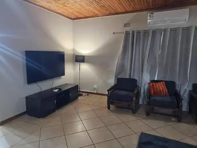 a living room with two chairs and a flat screen tv at The Bushveld Jasmine in Mokopane