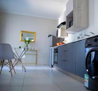 a kitchen with a washing machine and a table at Luxury on New in Midrand