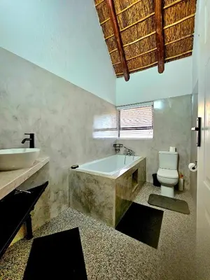 a bathroom with a tub and a toilet and a sink at Luxury GuesthouseCo RiverBend in Marloth Park