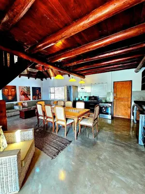 a living room with a wooden table and chairs at Luxury GuesthouseCo RiverBend in Marloth Park