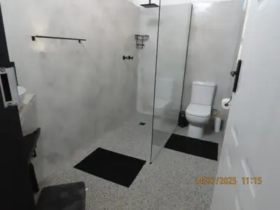 a bathroom with a toilet and a glass shower at Luxury GuesthouseCo RiverBend in Marloth Park