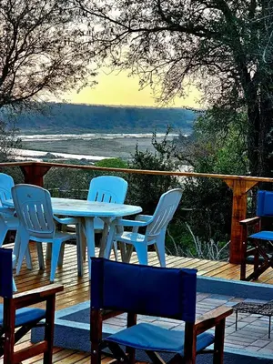 a table and chairs on a deck with a view at Luxury GuesthouseCo RiverBend in Marloth Park