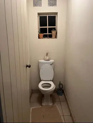 a small bathroom with a toilet with a window at Jenkins Stay in Pretoria