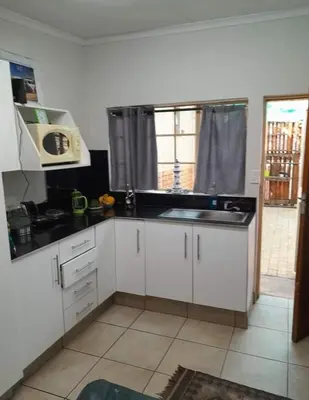 a kitchen with white cabinets and a sink and a window at Jenkins Stay in Pretoria