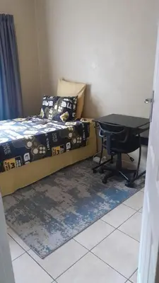 a bedroom with a bed and a table and a desk at Home away from home in Polokwane