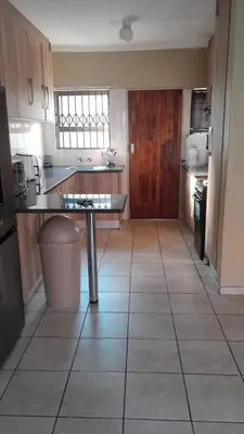 a kitchen with a tile floor and a table in it at Home away from home in Polokwane