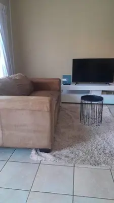 a living room with a couch and a flat screen tv at Home away from home in Polokwane