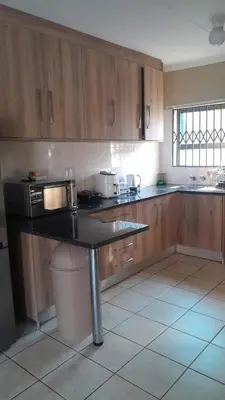 a kitchen with wooden cabinets and a black counter top at Home away from home in Polokwane