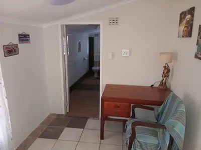 a hallway with a desk and a chair in a room at Laetari Guest House in Hartbeespoort