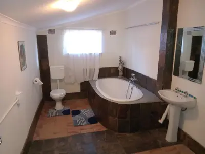 a bathroom with a tub and a toilet and a sink at Laetari Guest House in Hartbeespoort