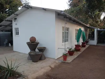 a white building with potted plants in front of it at Laetari Guest House in Hartbeespoort