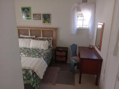 a bedroom with a bed and a desk and a window at Laetari Guest House in Hartbeespoort