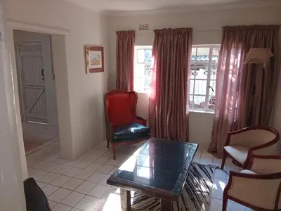 a living room with a table and chairs and a window at Laetari Guest House in Hartbeespoort