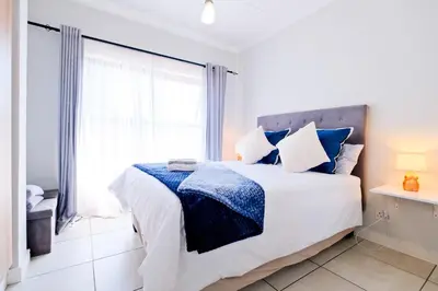 a white bedroom with a large bed and a window at Navy Lagoon Stay The Blyde in Pretoria