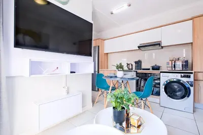 a kitchen with a washing machine and a table with chairs at Navy Lagoon Stay The Blyde in Pretoria