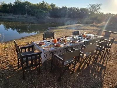 a table set up for a meal next to a lake at Tintshaba Safaris in Phalaborwa