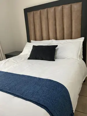a bed with a black pillow and white pillows at Luxstay in Nelspruit