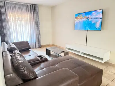 a living room with a leather couch and a flat screen tv at Luxstay in Nelspruit