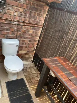 a toilet sitting next to a brick wall next to a picnic table at Kudu's Corner in Marloth Park