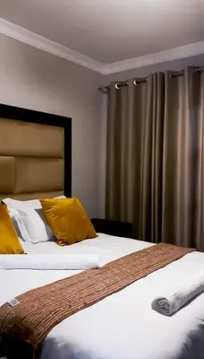 two beds with yellow pillows in a room at Nyakhosi Luxury Guesthouse in Thohoyandou