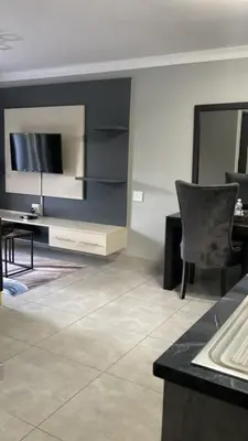 a living room with a television and a table and chair at Nyakhosi Luxury Guesthouse in Thohoyandou