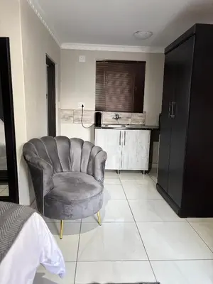 a living room with a chair and a kitchen at Nyakhosi Luxury Guesthouse in Thohoyandou