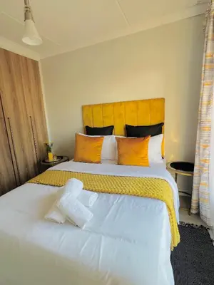 a bedroom with a large white bed with yellow pillows at Blyde Lagoon in Pretoria